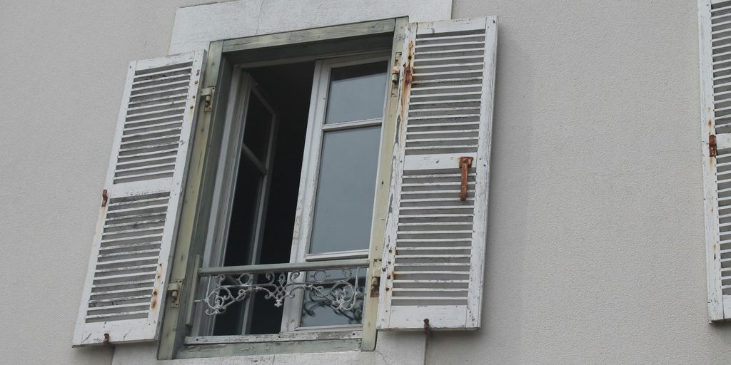 two windows with shutters open on a building